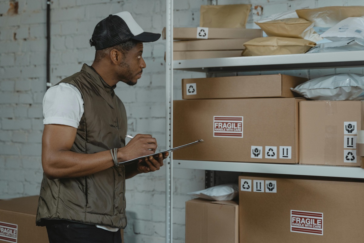 delivery worker checking packages on a shelf while writing something down