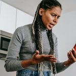 woman frowning while holding a smartphone