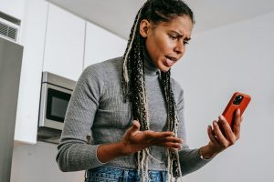 woman frowning while holding a smartphone